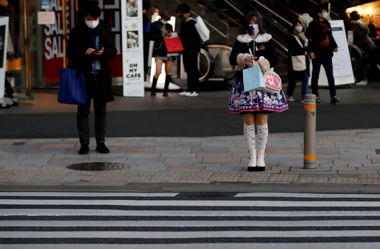 FILE PHOTO: Pedestrians wearing protective masks amid the coronavirus disease (COVID-19) outbreak stand in front of a cross walk at a shopping district in Tokyo, Japan, December 17, 2020. REUTERS/Kim Kyung-Hoon