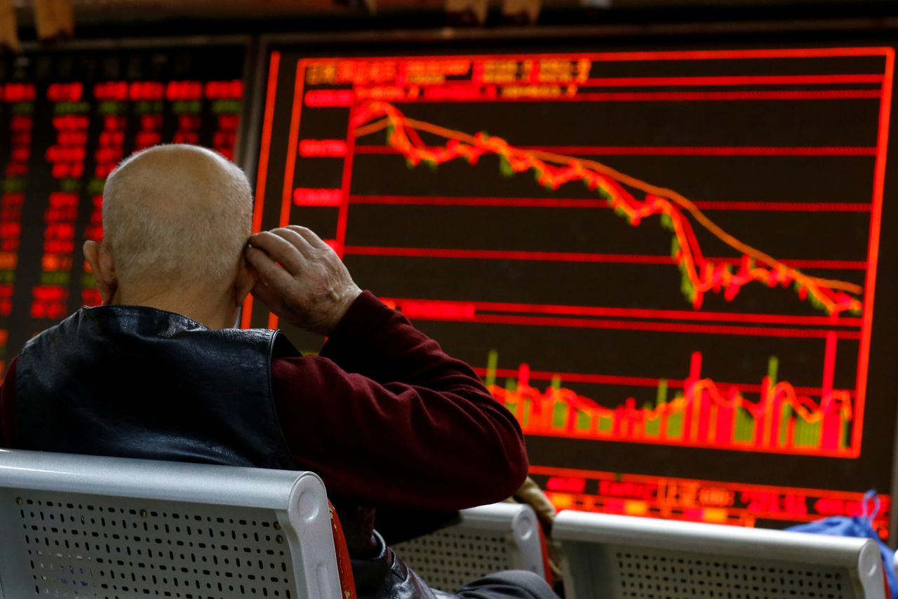 FILE PHOTO: An investor sits in front of a board showing stock information at a brokerage office in Beijing, China, December 7, 2018. REUTERS/Thomas Peter/File Photo
