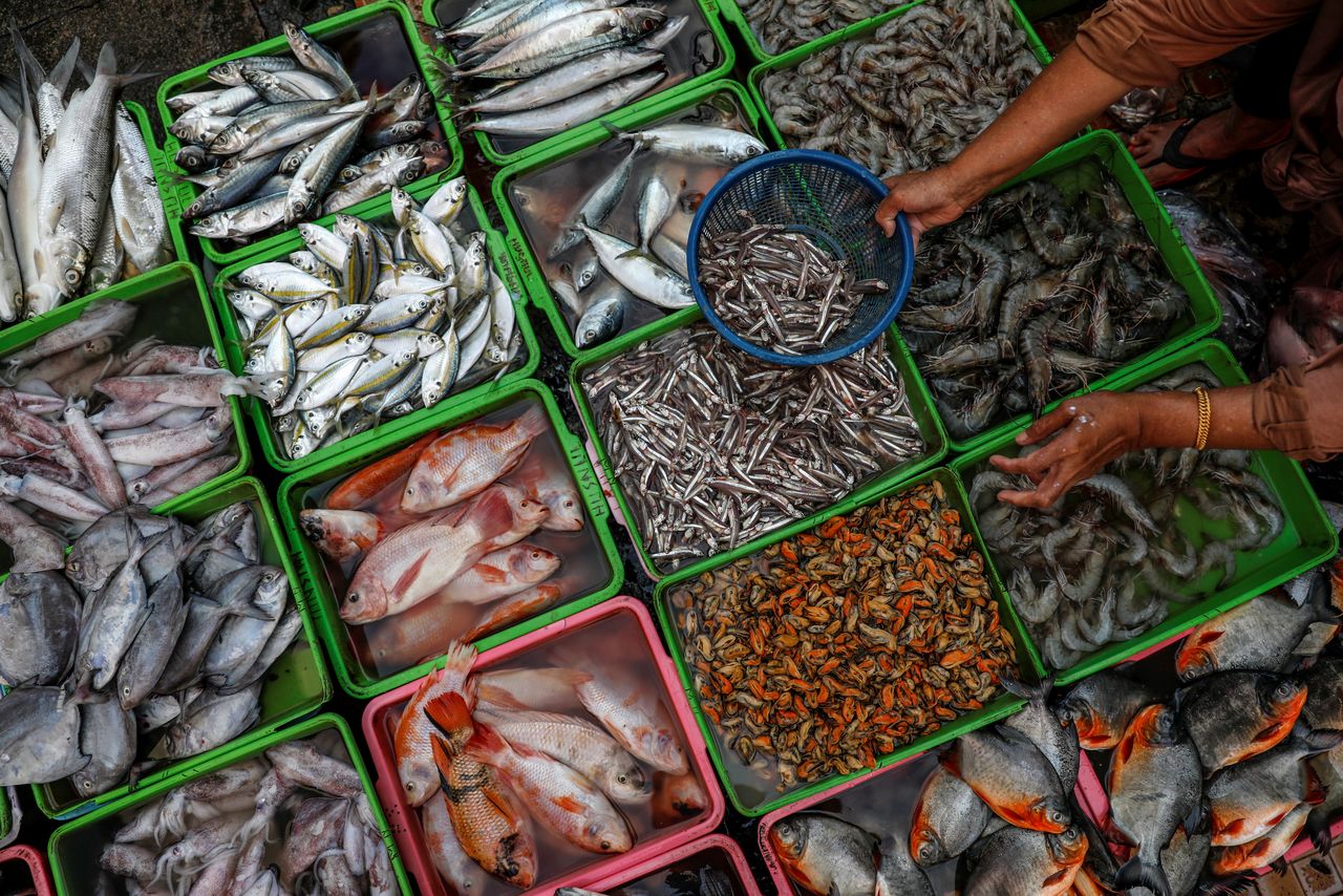 FILE PHOTO: A vendor selling seafood prepares fish as she serves her customers, at a traditional market in Jakarta, Indonesia, March 1, 2021. REUTERS/Willy Kurniawan/File Photo