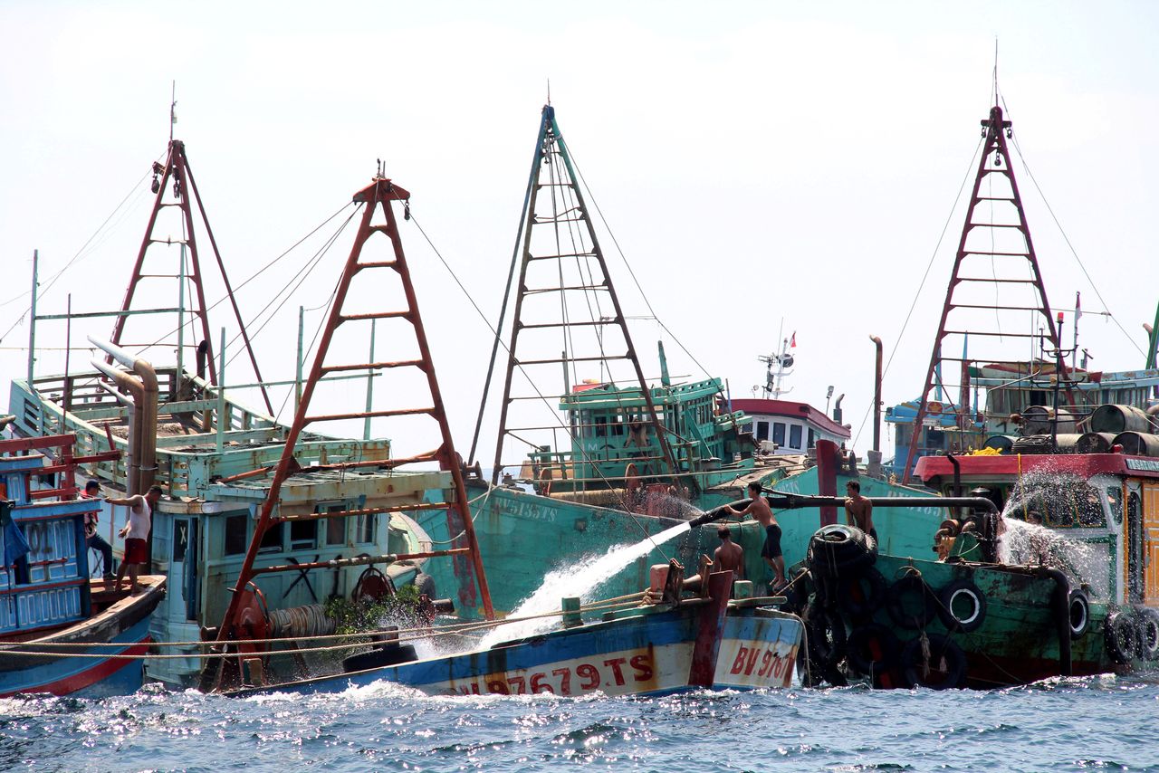 FILE PHOTO: Workers fill Vietnamese fishing boats with water to sink them after they were seized due to illegal fishing in Indonesia