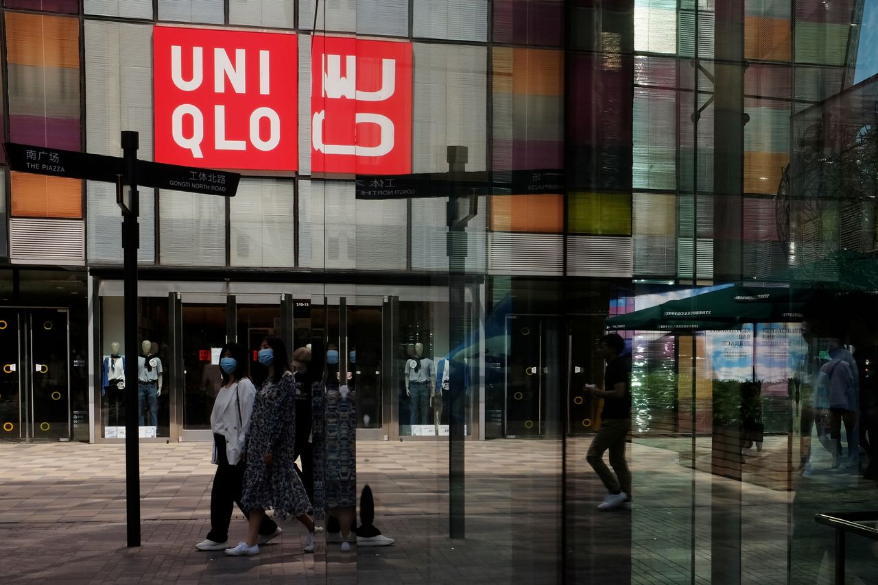 FILE PHOTO: Women wearing face masks, following the coronavirus disease (COVID-19) outbreak, walk past a store of Fast Retailing