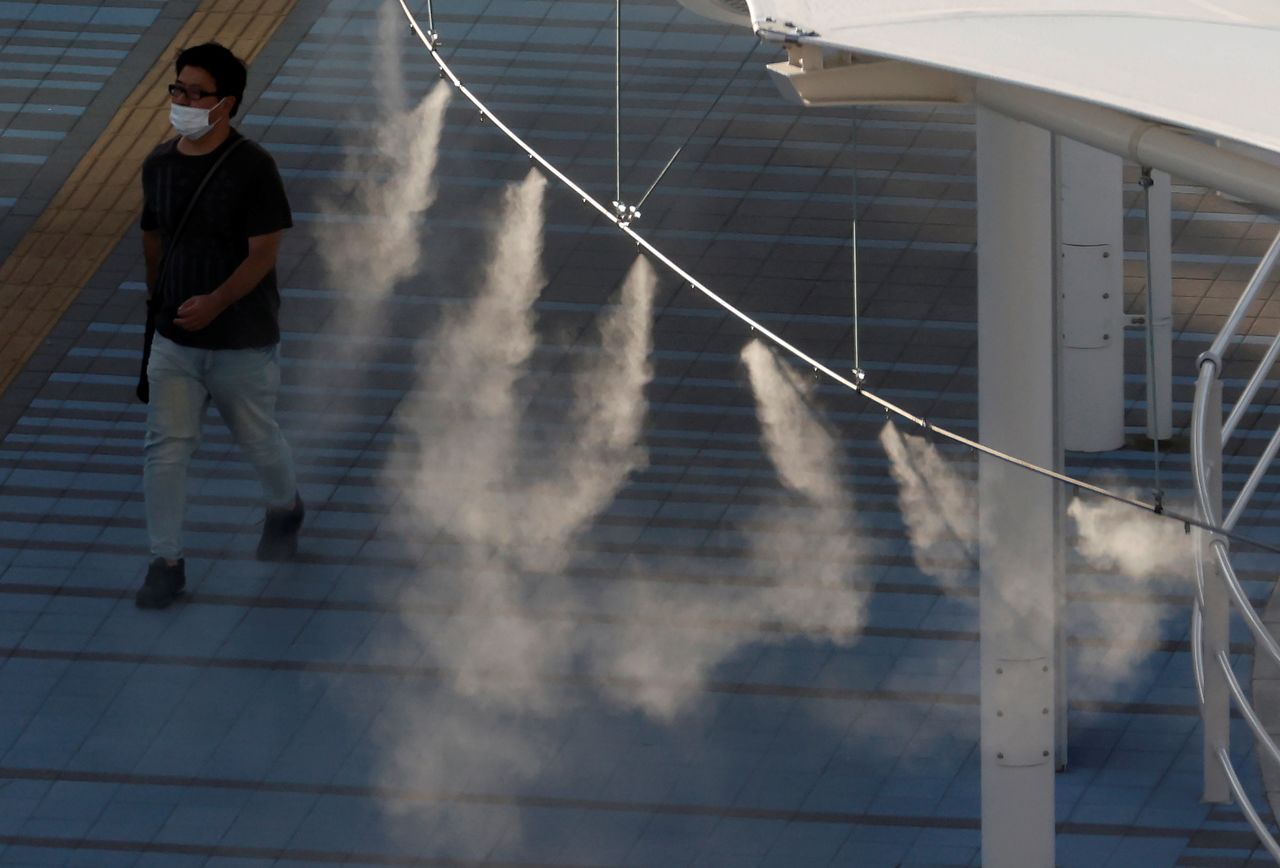 A man wearing a protective face mask walks beneath a cooling mist spray, ahead of the Tokyo 2020 Olympic Games that have been postponed to 2021 due to the coronavirus disease (COVID-19) pandemic, in Tokyo, Japan, July 15, 2021. REUTERS/Phil Noble