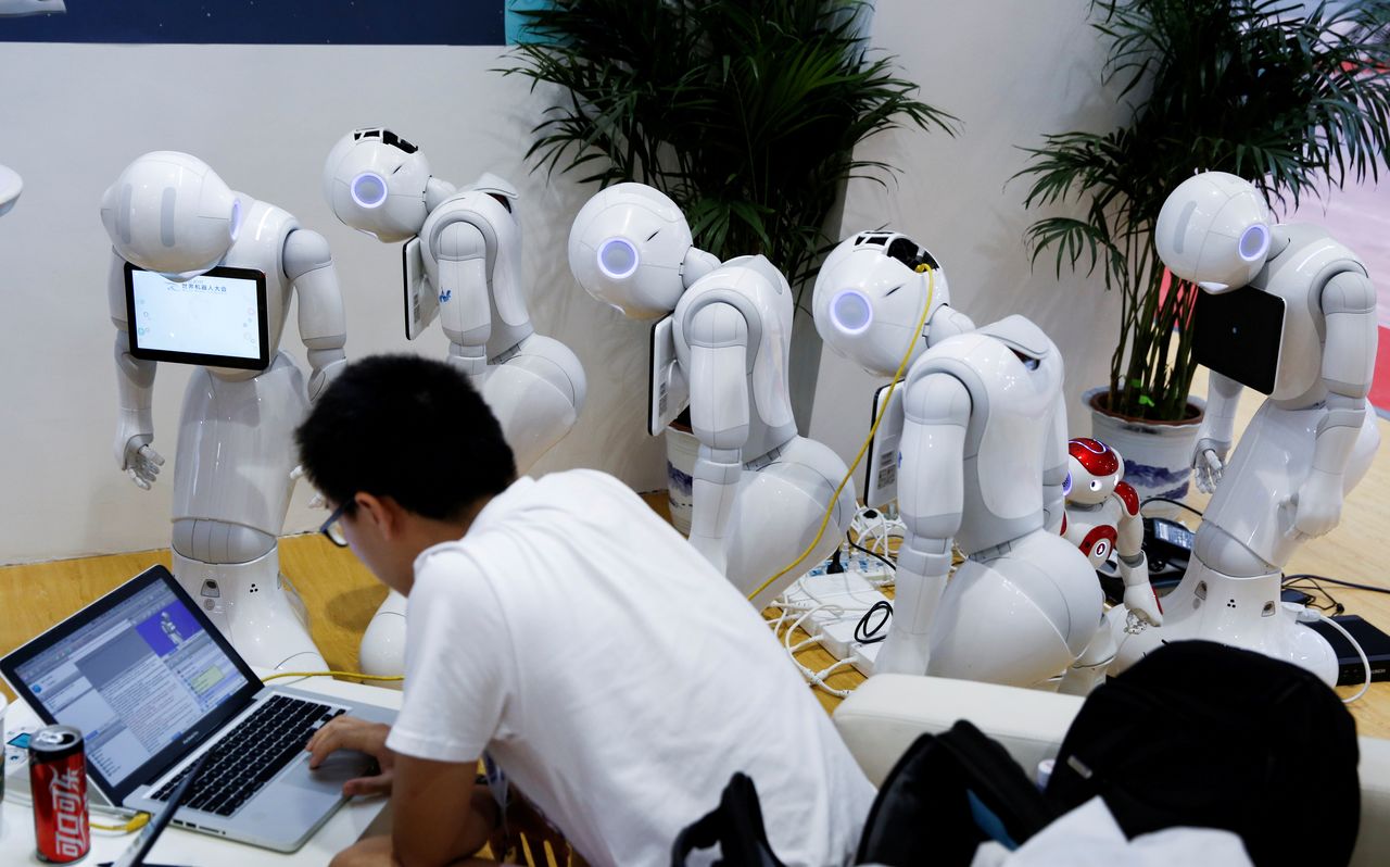 FILE PHOTO: A man programs SoftBank Robotics "Pepper" robots at the 2017 World Robot Conference in Beijing, China August 22, 2017. REUTERS/Thomas Peter/File Photo