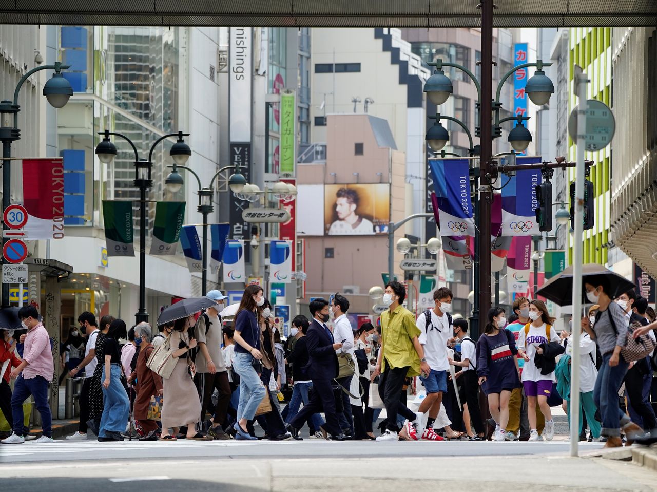 FILE PHOTO: Passersby wearing protective face masks walk under the street decoration of Tokyo 2020 Olympic and Paralympic Games that have been postponed to 2021 due to the coronavirus disease (COVID-19) outbreak, in Tokyo, Japan May 14, 2021. REUTERS/Naoki Ogura