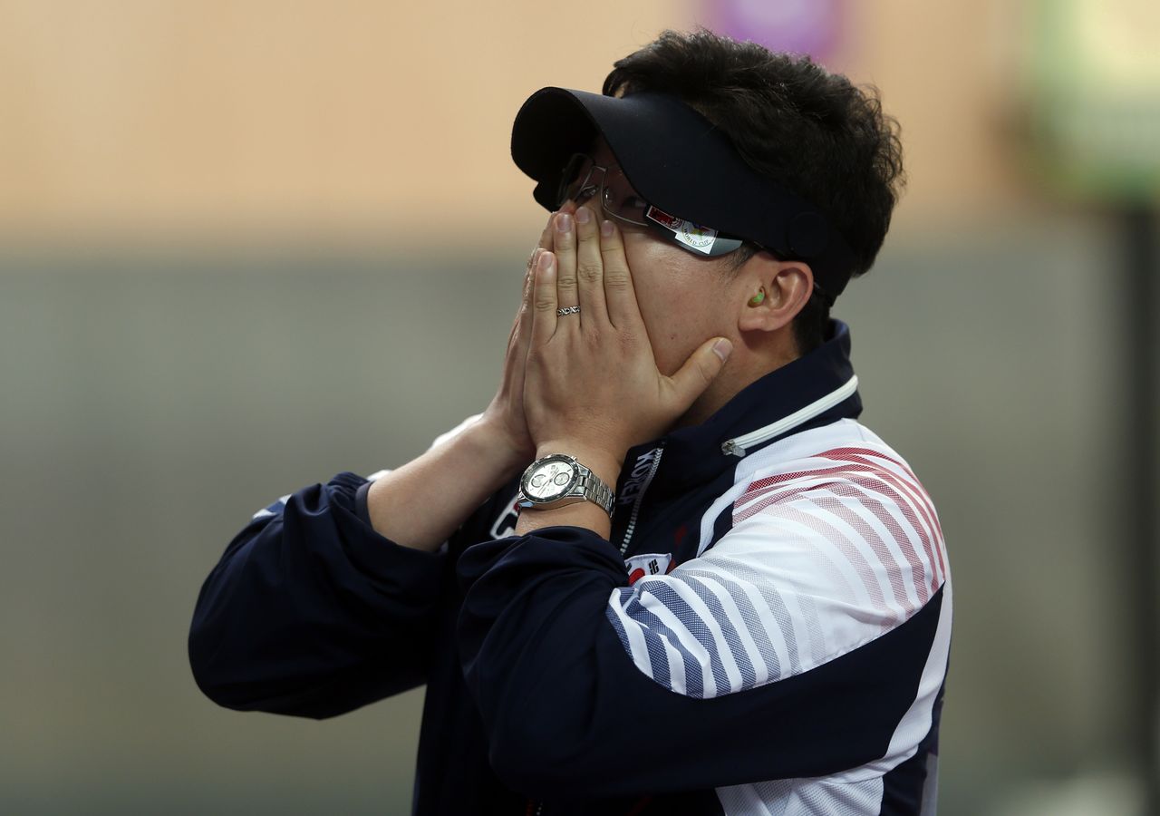 FILE PHOTO: South Korea's Jin Jong-oh covers his face after winning the men's 10m air pistol final at the London 2012 Olympic Games in the Royal Artillery Barracks at Woolwich in London July 28, 2012. REUTERS/Eddie Keogh