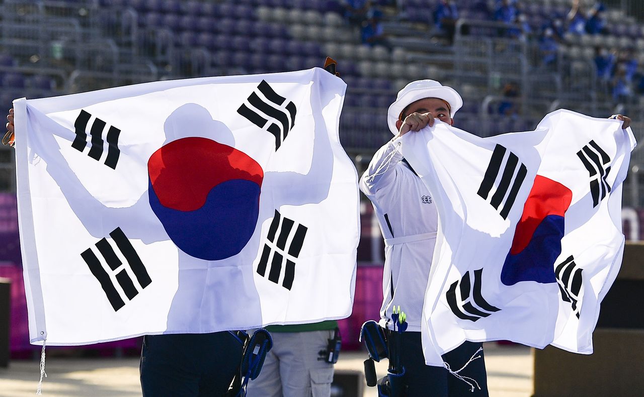 Tokyo 2020 Olympics - Archery - Mixed Team - Gold medal match - Yumenoshima Archery Field, Tokyo, Japan - July 24, 2021. An San of South Korea and Kim Je Deok of South Korea wave their national flags after winning gold REUTERS/Clodagh Kilcoyne