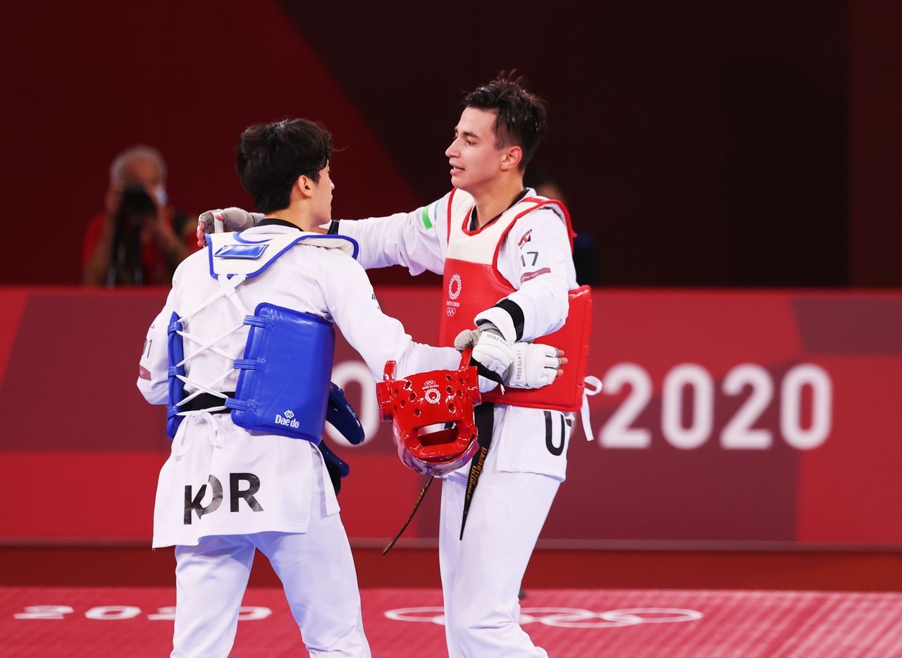 FILE PHOTO: Tokyo 2020 Olympics - Taekwondo - Men's Featherweight 58-68kg - Last 16 - Makuhari Messe Hall A, Chiba, Japan - July 25, 2021. Ulugbek Rashitov of Uzbekistan and Lee Dae-Hoon of South Korea embrace after competing REUTERS/Murad Sezer