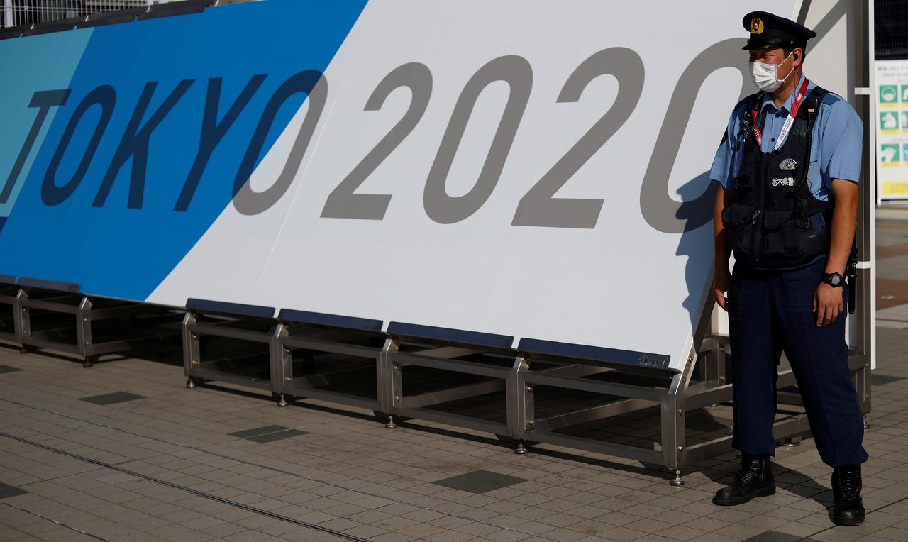 FILE PHOTO: A police officer wearing a face mask stands near the entrance of the Main Press Centre, ahead of the Tokyo 2020 Olympic Games, in Tokyo, Japan, July 19, 2021. REUTERS/Phil Noble