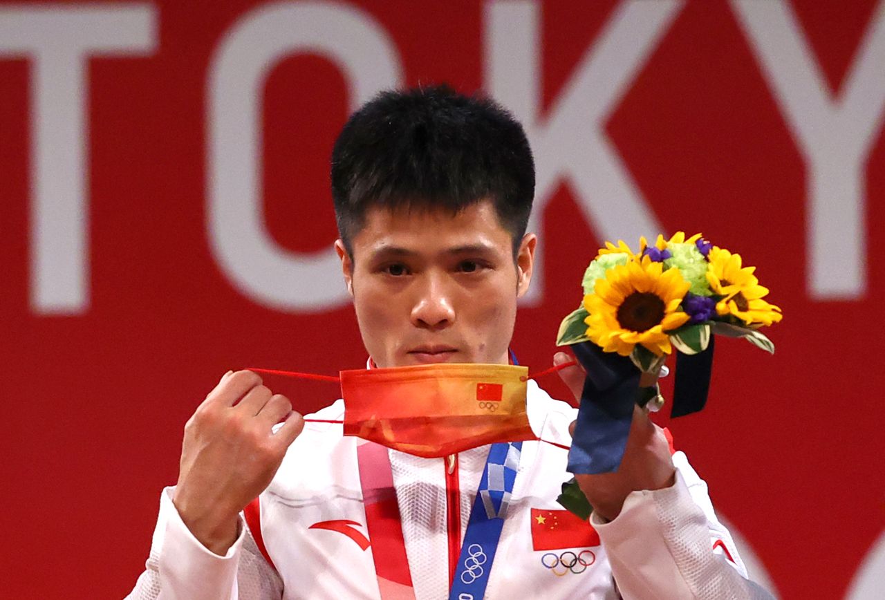 Tokyo 2020 Olympics - Weightlifting - Men's 61kg - Medal Ceremony - Tokyo International Forum, Tokyo, Japan - July 25, 2021. Gold medalist Li Fabin of China adjusts his mask. REUTERS/Edgard Garrido