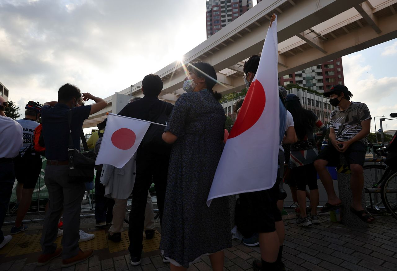 Tokyo 2020 Olympics - Triathlon - Men's Olympic Distance - Final - Odaiba Marine Park, Tokyo, Japan July 26, 2021. Fans and local residents try to catch a glimpse of the men's triathlon event. REUTERS/Issei Kato