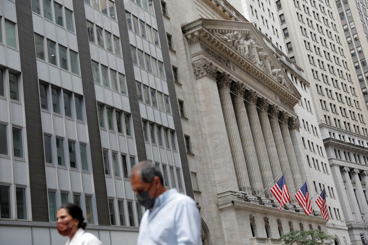FILE PHOTO: People wearing face masks walk by the New York Stock Exchange (NYSE) during the outbreak of the coronavirus disease (COVID-19) in New York City, New York, U.S., July 19, 2021. REUTERS/Andrew Kelly