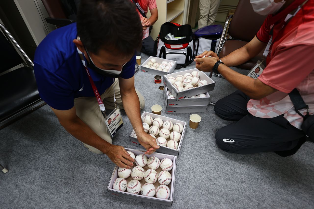 Umpiring officials rub baseballs with mud prior to a game during the Tokyo 2020 Olympics at the Yokohama Baseball Stadium in Yokohama, Japan July 30, 2021. REUTERS/Jorge Silva