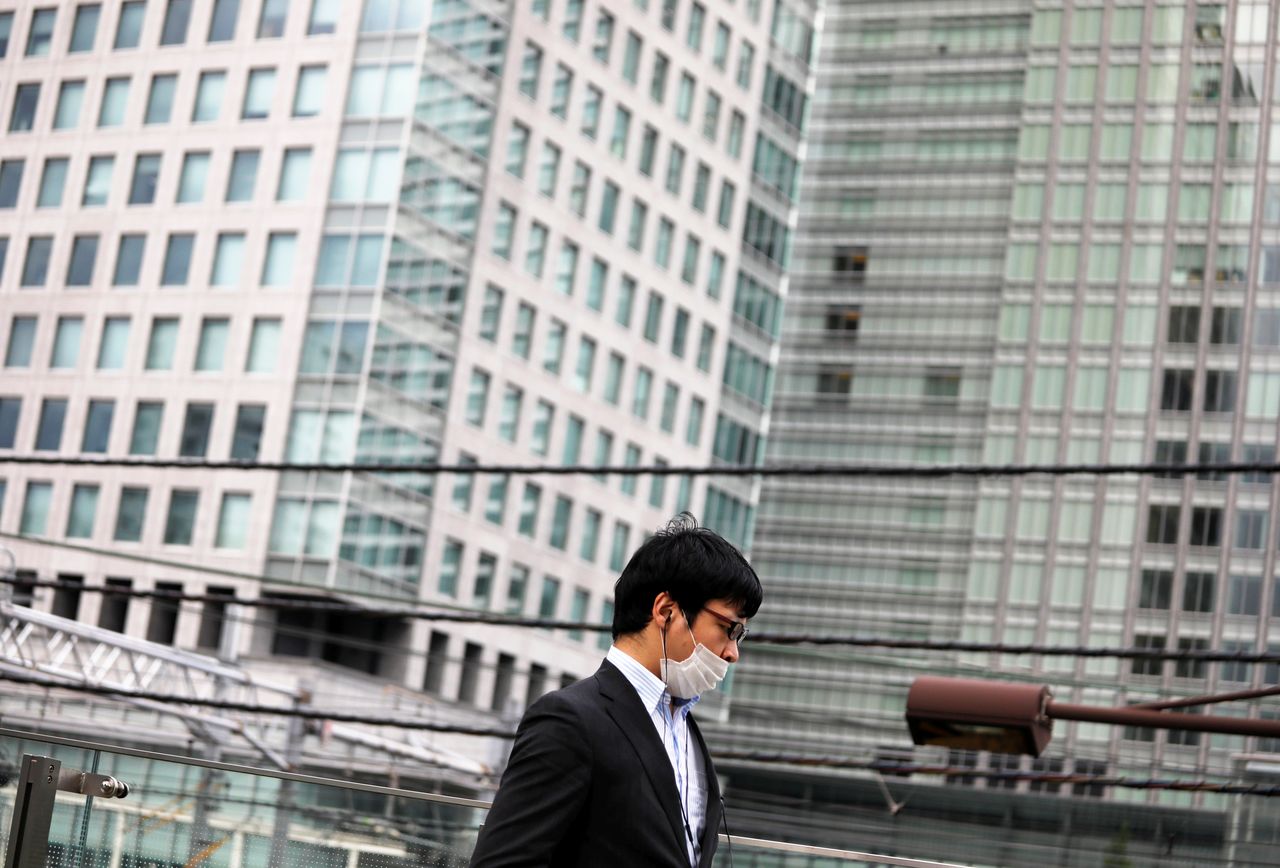 FILE PHOTO: A businessman wearing a protective face mask walks near the station amid the coronavirus disease (COVID-19) outbreak in Tokyo, Japan July 30, 2020. REUTERS/Issei Kato