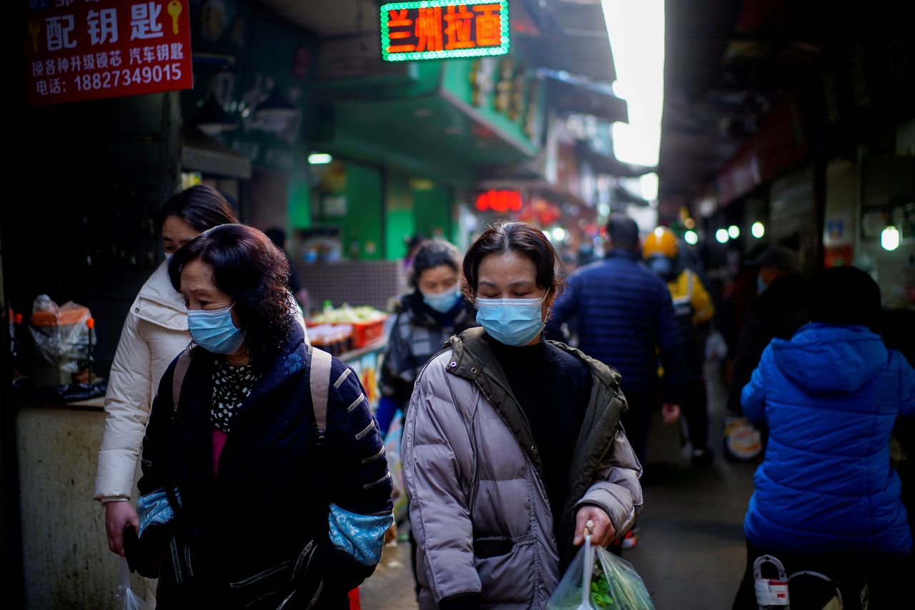 FILE PHOTO: People wearing face masks walk on a street market, following an outbreak of the coronavirus disease (COVID-19) in Wuhan, Hubei province, China February 8, 2021. REUTERS/Aly Song