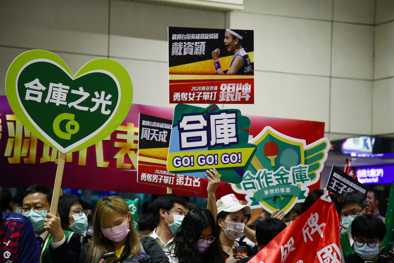 Supporters hold signs at Taoyuan International Airport as they wait for Olympic athletes