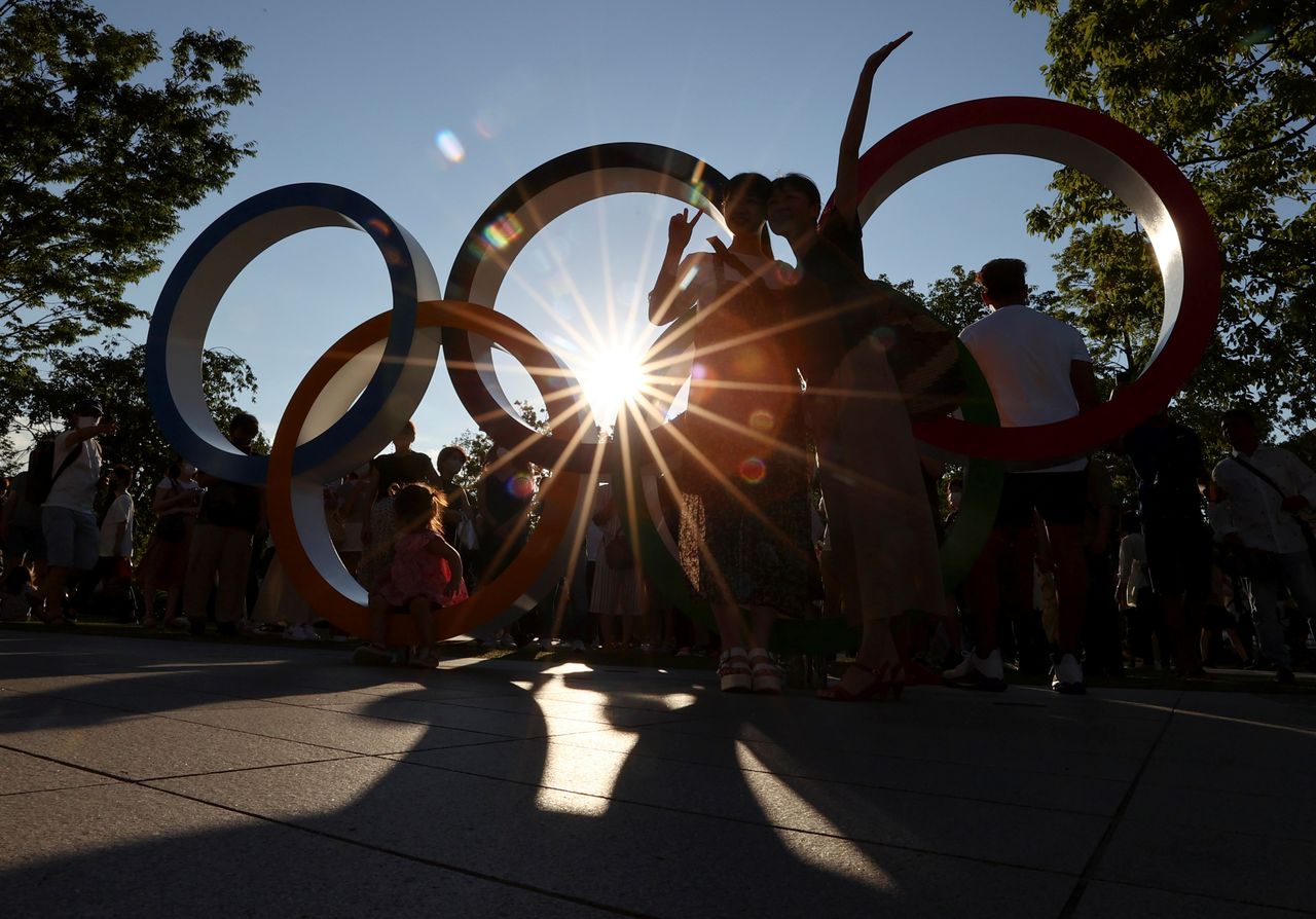 FILE PHOTO: People pose for a photograph in front of an Olympic rings monument outside the National Stadium, the main stadium of Tokyo 2020 Olympic and Paralympic Games, amid the coronavirus disease (COVID-19) pandemic, in Tokyo, Japan July 31, 2021. REUTERS/Issei Kato