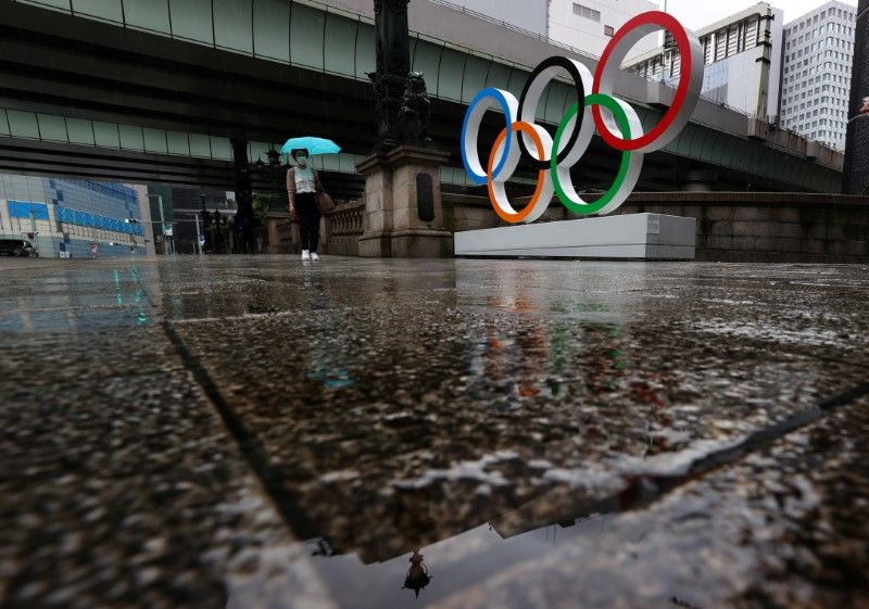 A woman wearing a protective face mask, amid the coronavirus disease (COVID-19) outbreak, walks past the Olympic Rings on the last day of Tokyo 2020 Olympic Games, in Tokyo, Japan, August 8, 2021. REUTERS/Kim Kyung-Hoon