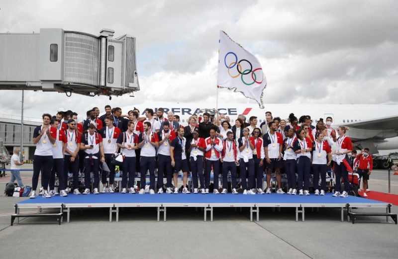 Olympics - French Olympic medallists arrive with the Olympic flag in Paris - Roissy Charles de Gaulle airport, Paris, France - August 9, 2021 Mayor of Paris Anne Hidalgo poses as she holds the Olympic flag with President of the Paris 2024 Organising Committee Tony Estanguet and french Olympic medallists as they arrive at Roissy Charles de Gaulle airport REUTERS/Sarah Meyssonnier