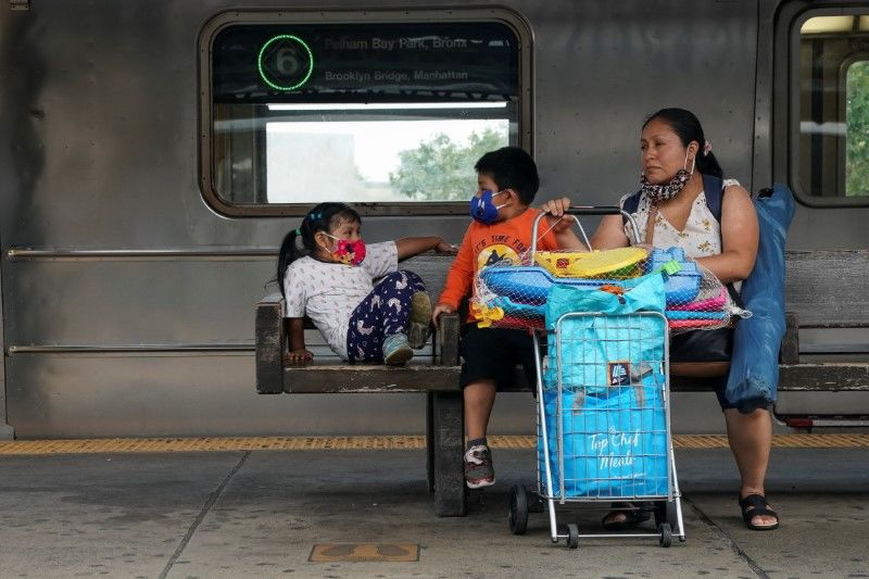 FILE PHOTO: A person and two children wearing face masks due to the coronavirus disease (COVID-19) pandemic wait for the subway in the Bronx borough of New York City, U.S., July 27, 2021. REUTERS/David