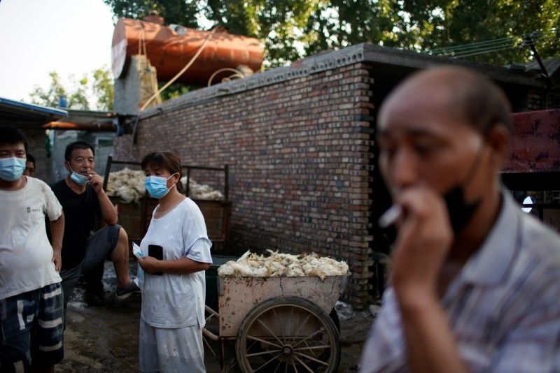 Zhang Guangsi, a 53-year-old farmer, smokes a cigarette next to a wheelbarrow filled with chicken carcasses after heavy rainfall flooded Wangfan village of Xinxiang, Henan province, China July 25, 2021. Picture taken July 25, 2021. REUTERS/Aly Song
