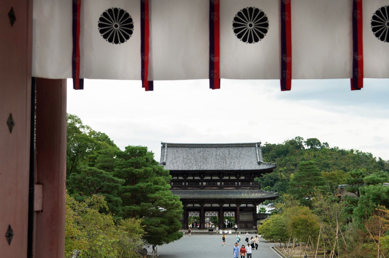 La puerta niōmon vista desde la entrada, de la que cuelga una tela estampada con el escudo del crisantemo, que representa a la casa imperial. El recinto del Ninna-ji puede recorrerse de forma gratuita, pero la entrada al Palacio, al Reihōkan y a las exposiciones especiales es de pago.