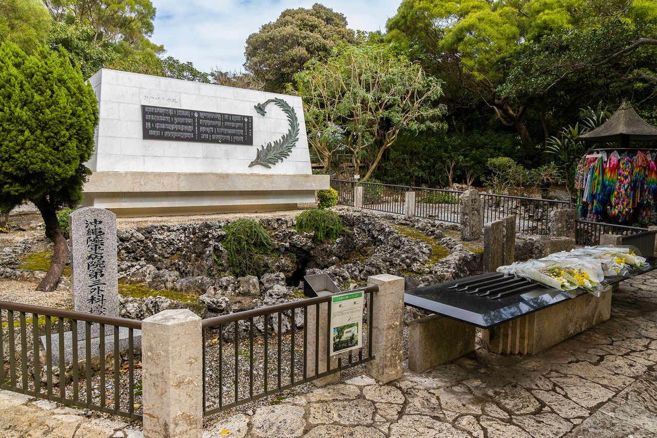 Boca de la Cueva de la III Unidad Quirúrgica de Ihara (municipio de Itoman, Okinawa) con placa conmemorativa y varias lápidas alrededor.