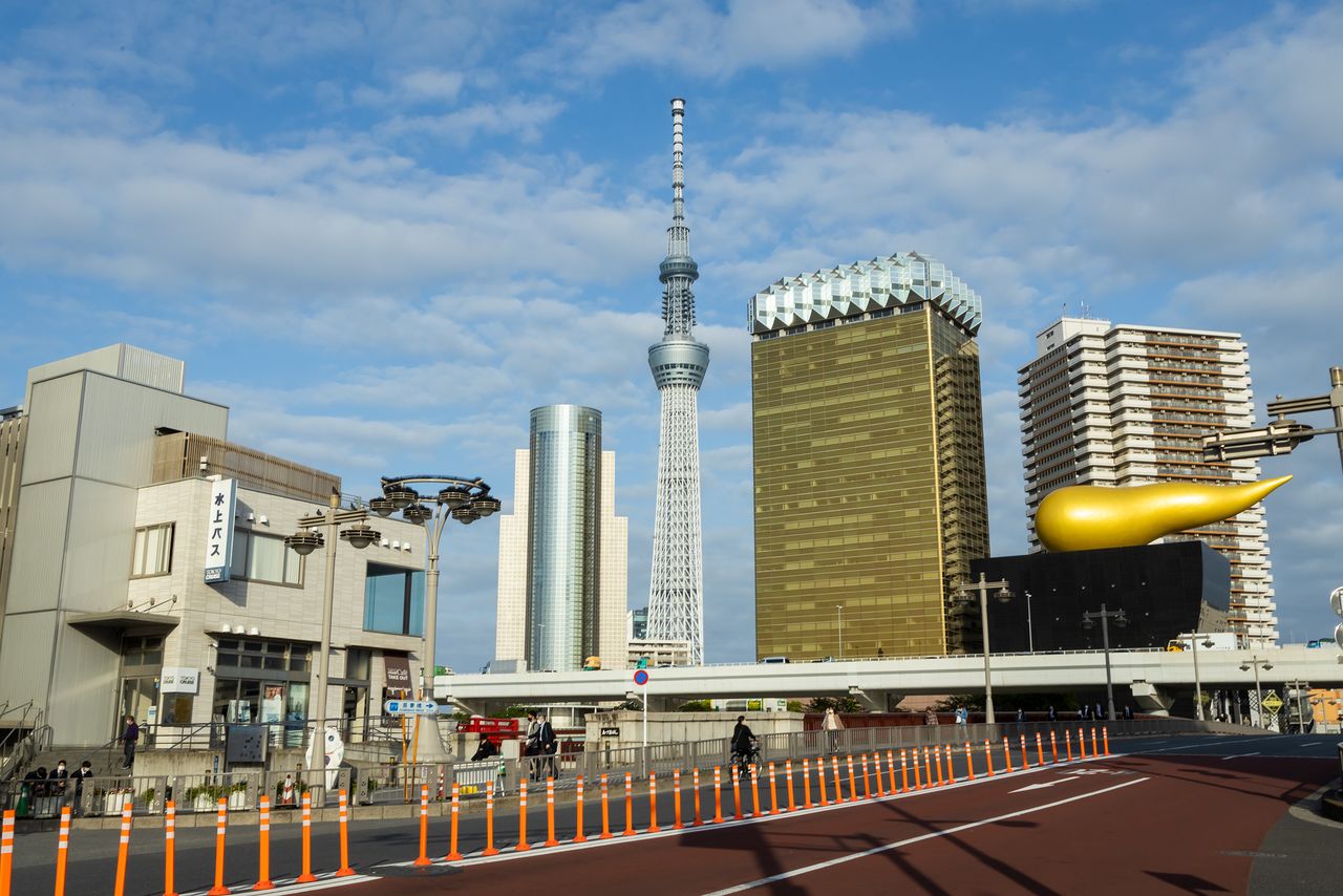 La Tokyo Skytree detrás del puente Azuma vista desde las cercanías de la estación de Asakusa. La torre se ha convertido en un elemento más del paisaje típico de la zona, junto con el edificio de la sede de la cervecería Asahi, con forma de tarro de cerveza, y el objeto dorado.
