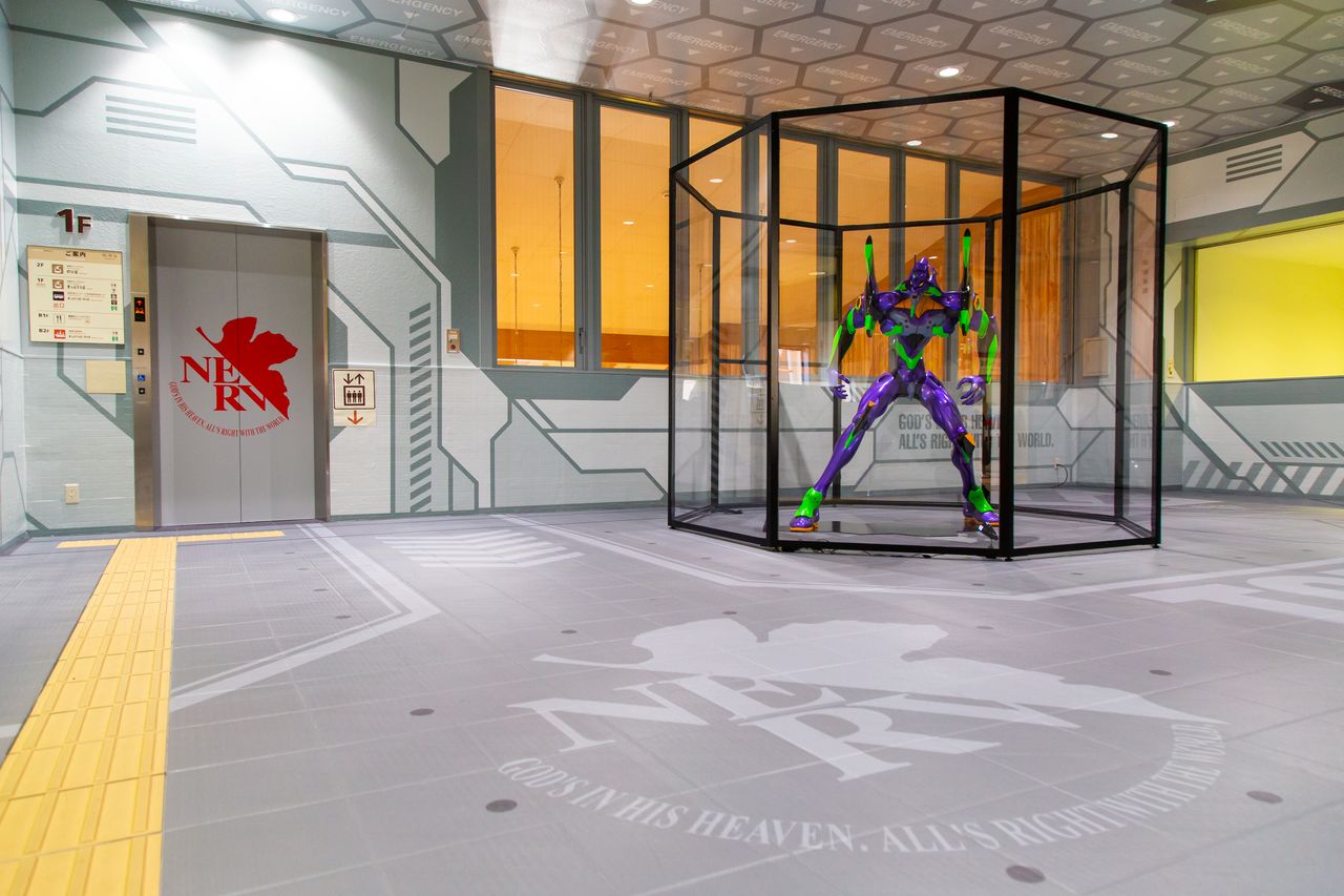 Toda la sala, incluidas las paredes, el piso y las puertas del ascensor, está decorada con motivos de la sede de Nerv.