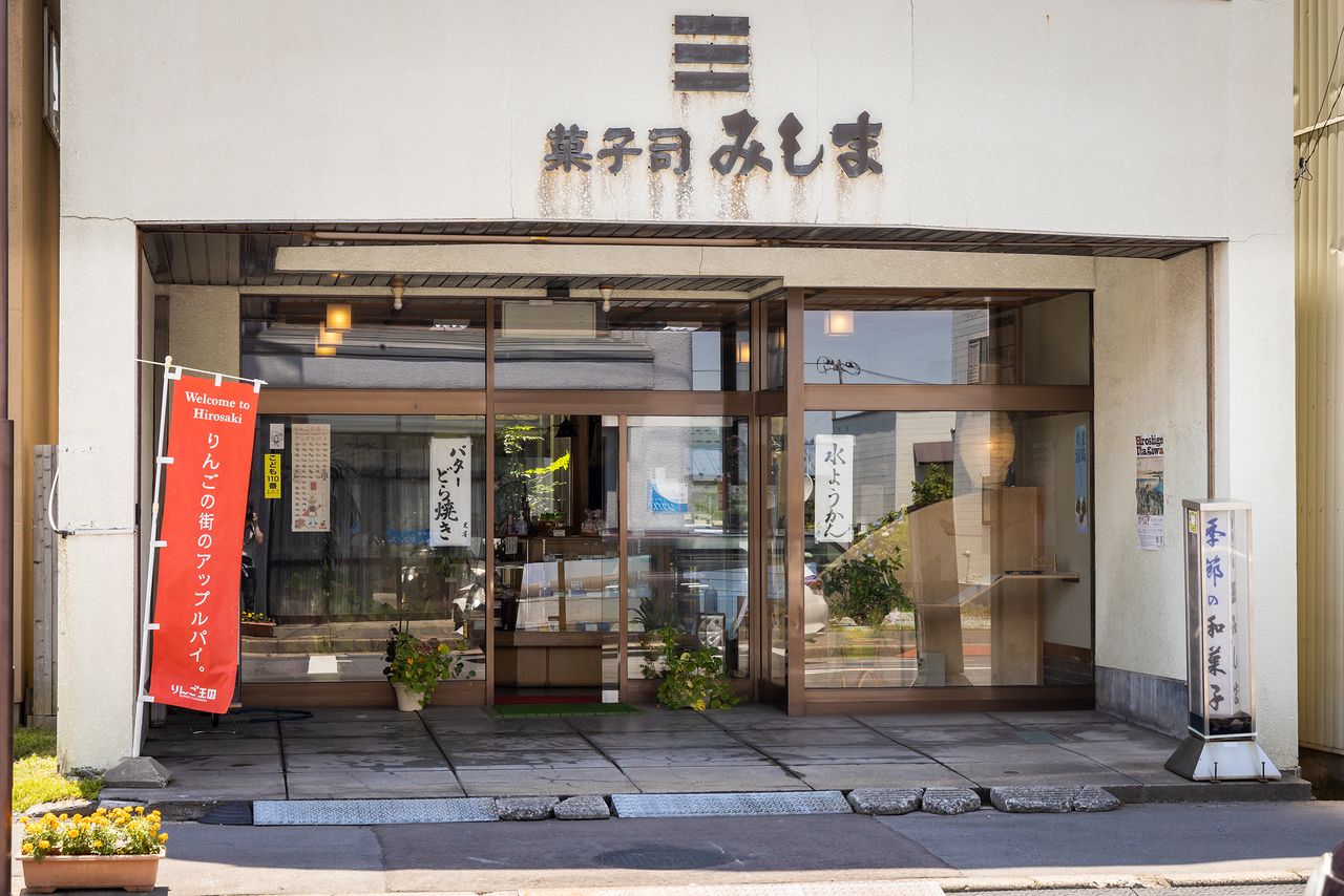 La dulcería tradicional Kashitsukasa Mishima fundada en 1905 (Watoku-machi 39, ciudad de Hirosaki). En la entrada del establecimiento hay una banderola que promociona las “tartas de manzana de la ciudad de las manzanas”. 