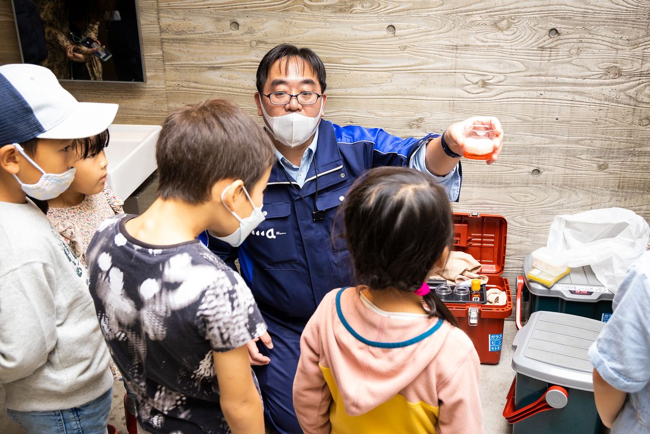 Yamato, especialista en baños, explicando a los niños los resultados que se obtienen utilizando diferentes detergentes.