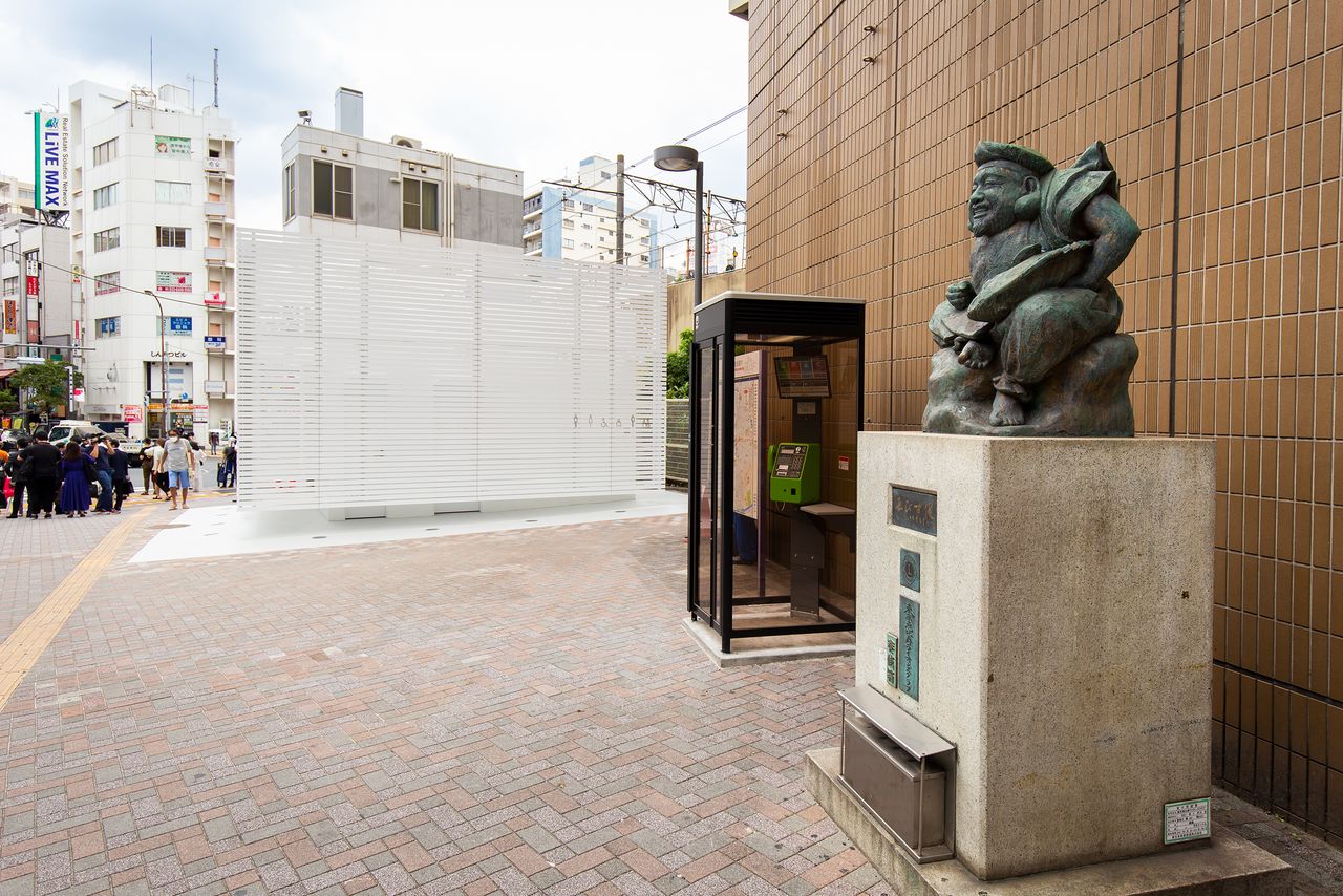 La estatua de la deidad Ebisu que vela el baño público de la salida oeste de la estación homónima.