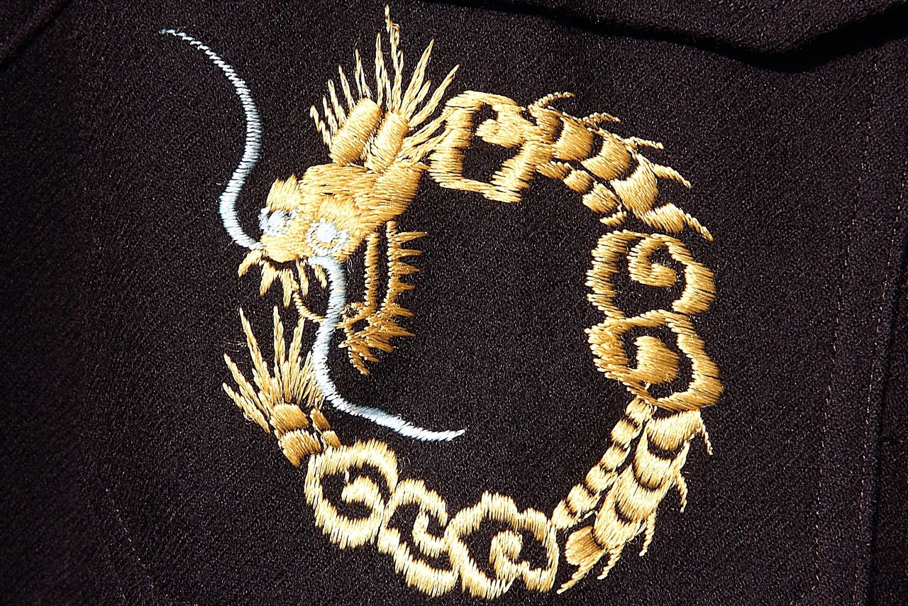Un dragón de bordado fino. Detalle del bolsillo frontal de la sukajan con un águila y la bandera estadounidense.