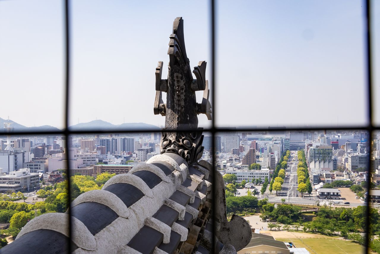 La vista de la avenida Ōtemae desde el último piso del torreón, detrás del animal mitológico shachihoko.