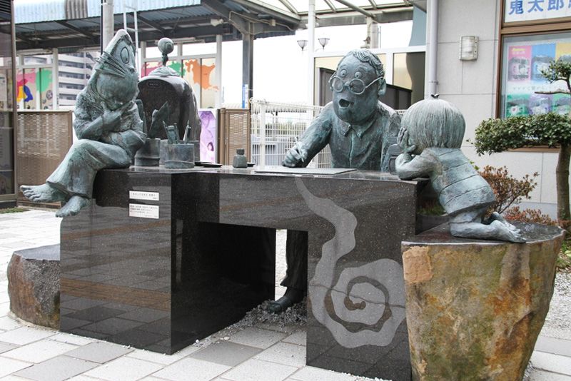 Una estatua frente a la estación de Sakaiminato muestra a Mizuki Shigeru escribiendo rodeado de algunos de sus personajes. (© Nippon.com)