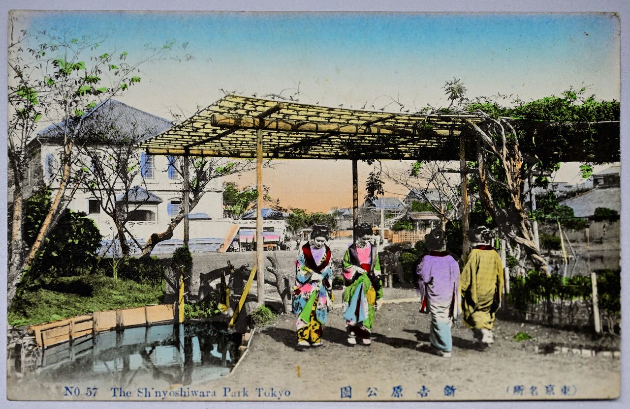Prostitutas pasean por el parque Nuevo Yoshiwara en esta postal de la era Taishō hecha a partir de una fotografía en blanco y negro coloreada (colección particular). Puede apreciarse un puente y el agua del estanque de Benten a ambos lados. 