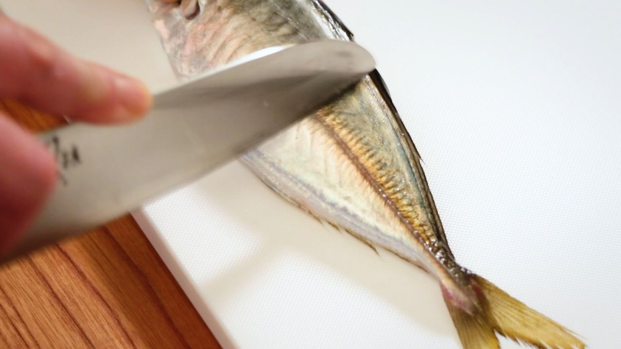 Mantenga el cuchillo perpendicular al costado del pescado y raspe las escamas.