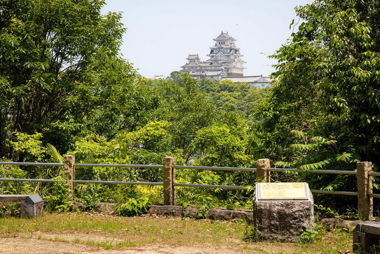 La vista del castillo con el monumento conmemorativo de las “Diez mejores vistas del castillo de Himeji”. Normalmente se pueden apreciar las atalayas pasadizo del recinto nishinomaru, pero en esta fotografía el follaje de los árboles las ocultó.
