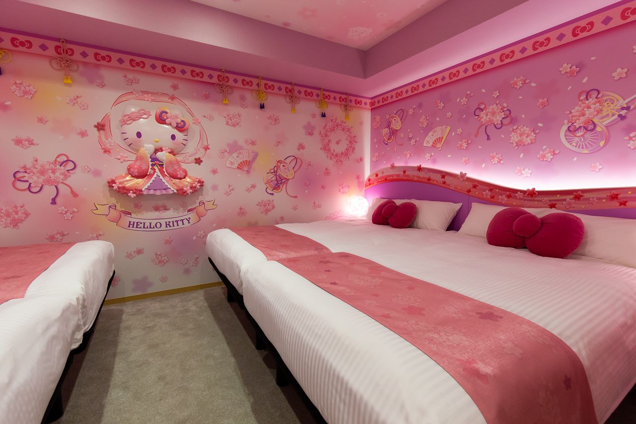 La habitación sakura tennyo. En el centro de la pared hay un relieve de Kitty, que se convertirá en un fondo fabuloso para una foto en Instagram. Las almohadas con forma de lazo son un detalle muy lindo. 