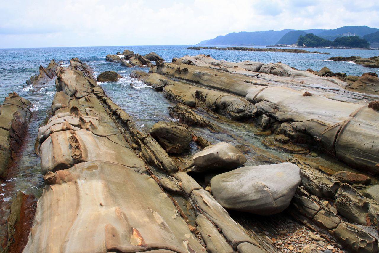 Las rocas raras alineadas en la playa de Tatsukushi. Sus nombres, Ōtake y Kotake, “bambú grande” y “bambú pequeño”, respectivamente, se deben a las líneas en las rocas rectas parecidas a los nudos de troncos de bambú. (Imagen de PIXTA)