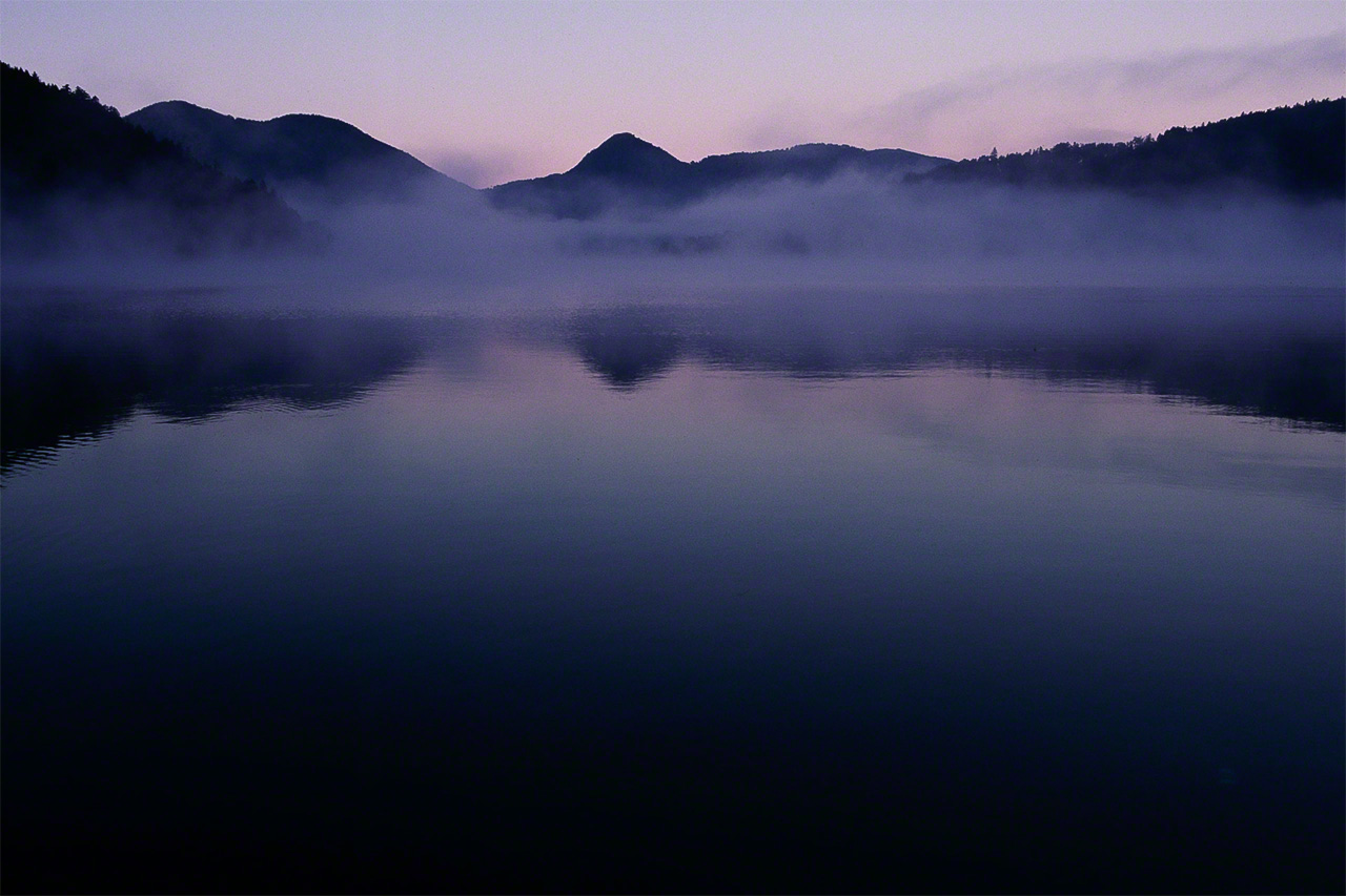 El lago Shikaribetsu al alba, coronado por la niebla. Se trata de un lago embalsado que se form&oacute; cuando una erupci&oacute;n volc&aacute;nica obstruy&oacute; el r&iacute;o. A sus 810 metros de altitud, es el lago m&aacute;s elevado de Hokkaidō. Se halla en el parque nacional Daisetsuzan.