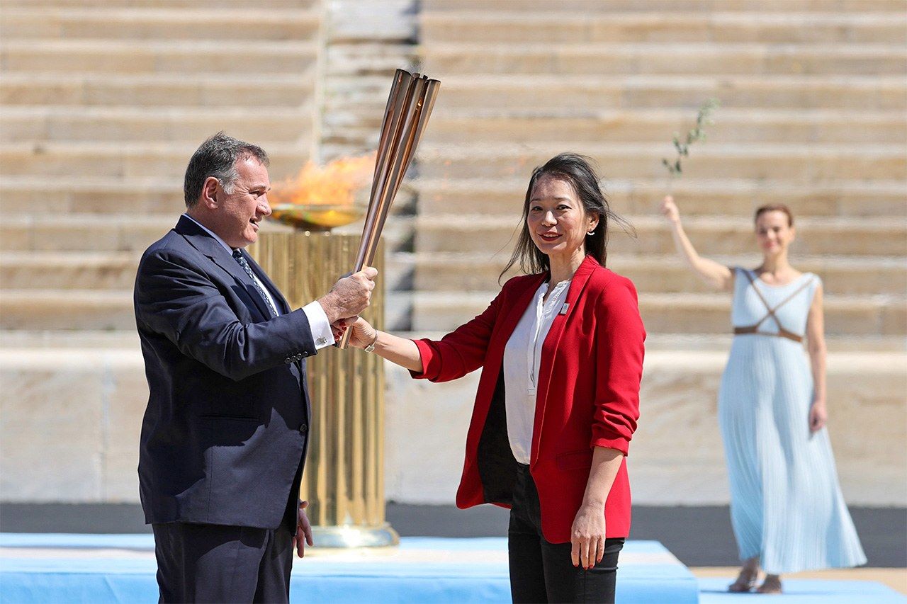 Recibiendo la antorcha del presidente del Comité Olímpico Helénico, Spyros Capralos (Jiji Press).
