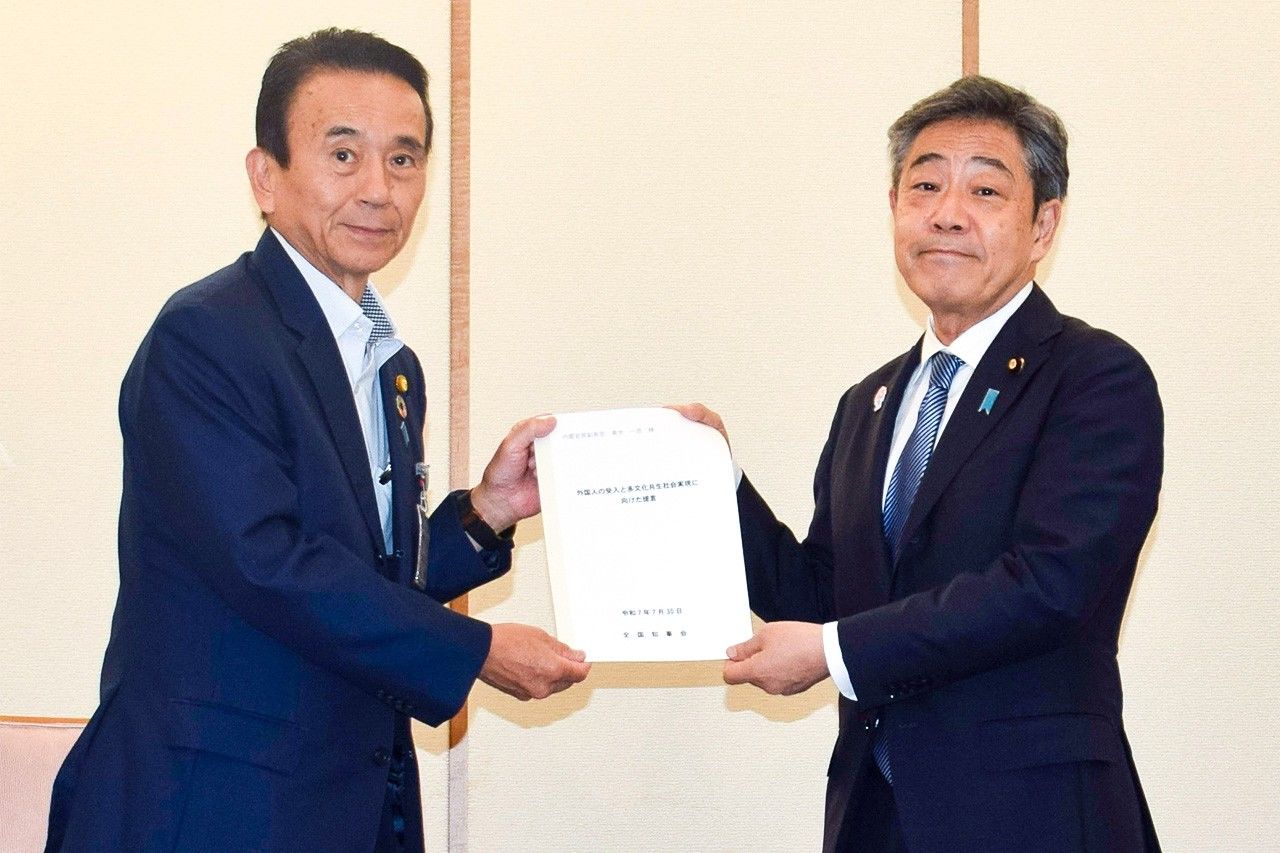 El gobernador de Shizuoka Suzuki Yasutomo (izquierda) entrega la propuesta sobre la aceptación de extranjeros de la Asociación Nacional de Gobernadores al vicesecretario jefe del Gabinete Aoki Kazuhiko. Nagatachō, Tokio, 20 de julio de 2025. (Jiji press)