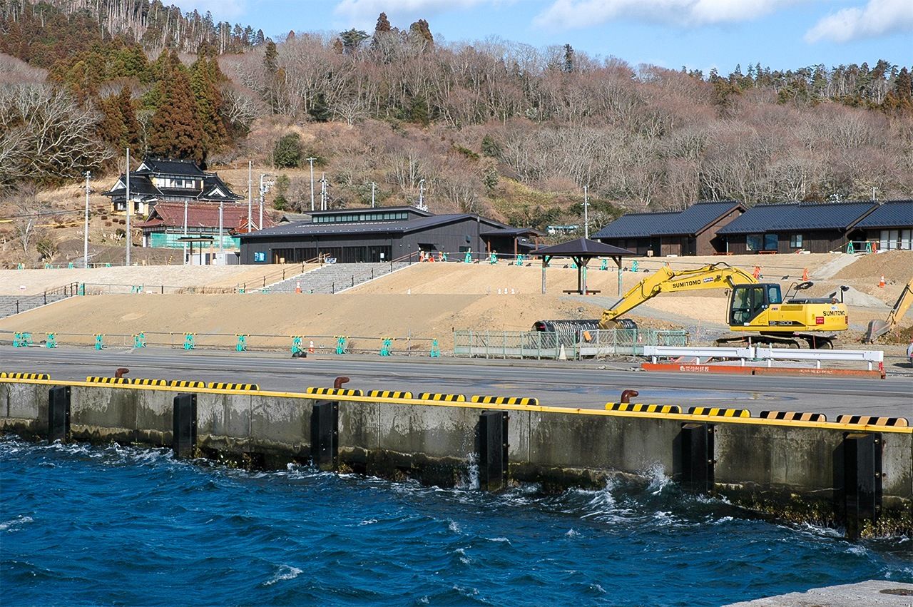 El puerto pesquero de Ura-no-hama en Ōshima. Los terrenos en la parte posterior del rompeolas fueron elevados a la misma altura del rompeolas y la cara que da al mar se cubrió de plantas para disimular la pared de hormigón. 