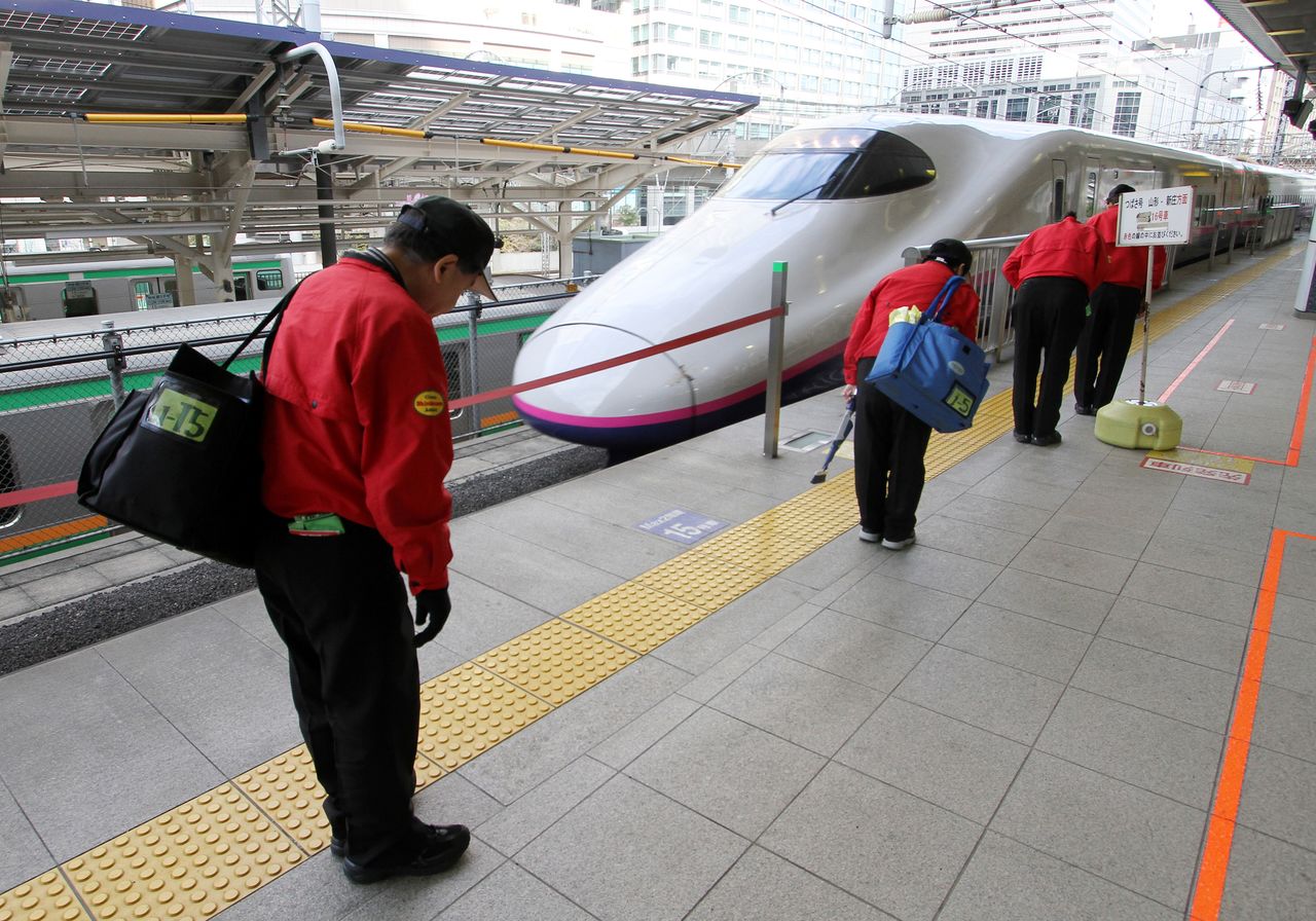 Personal de limpieza del Shinkansen saludando a los viajeros a la llegada de un tren a la estación de Tokio. (PIXTA)