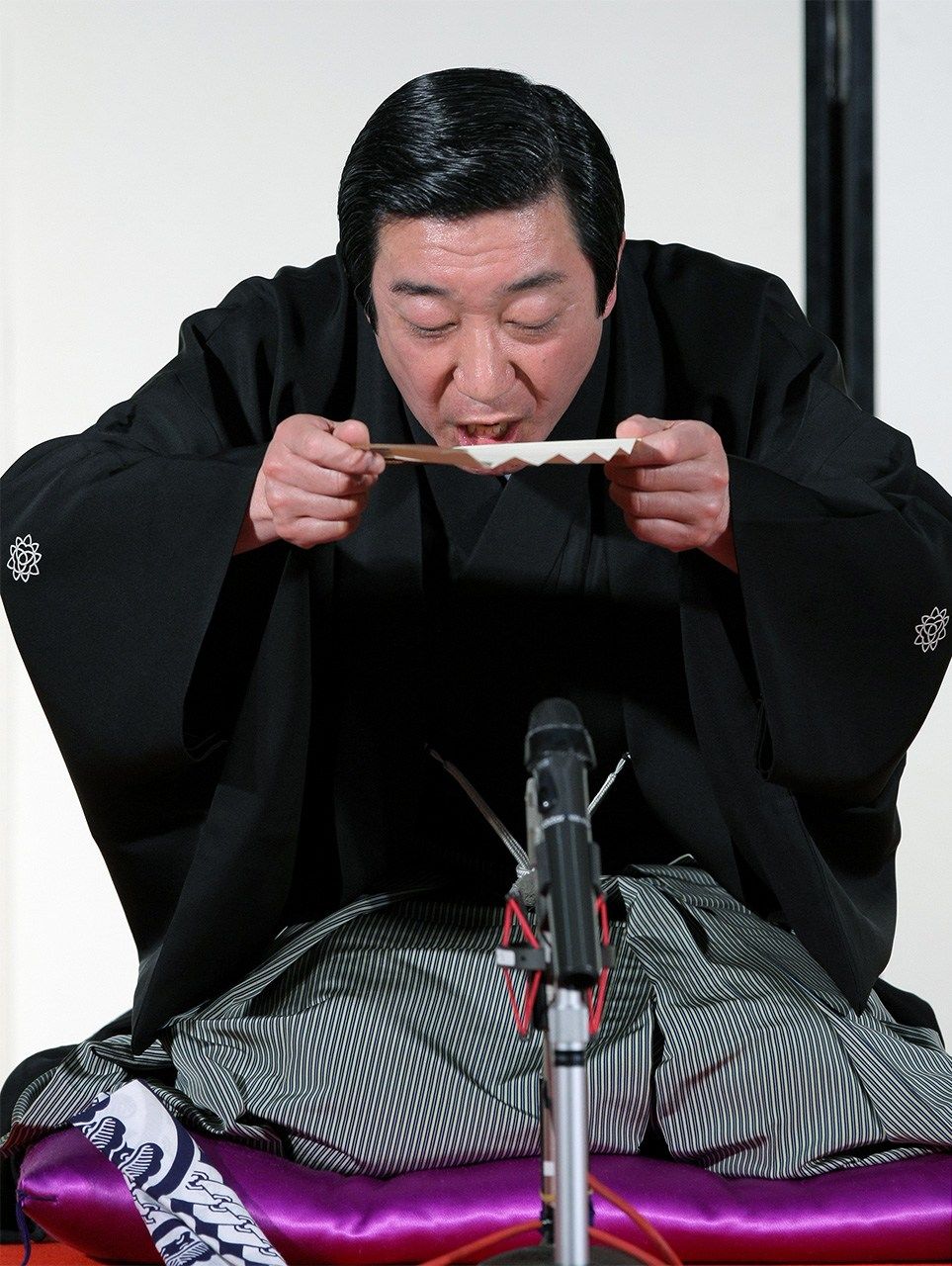 El monologuista de rakugo Sanyūtei Hōraku utiliza un abanico para hacer como si estuviera bebiendo sake durante una de sus actuaciones. (Jiji Press)