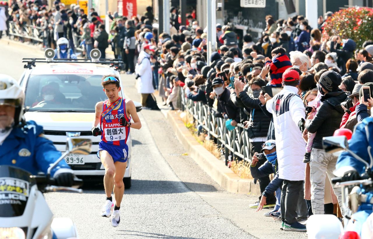 Ishizu Yoshiaki, del equipo de la Universidad Sōka, corre airosamente ante la multitud congregada en Tsurumi-ku (Yokohama) en la vuelta de la 97 edición del Ekiden de Hakone, el 3 de enero de 2021. (Jiji Press)