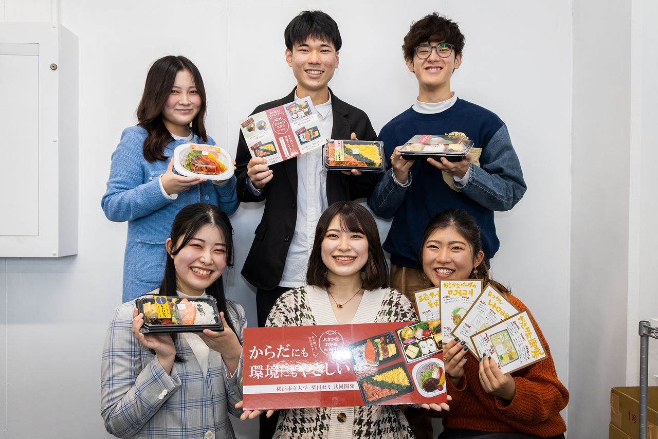 Estudiantes del seminario Shibata posando con carteles, panfletos y los almuerzos, un día antes de su lanzamiento al mercado.