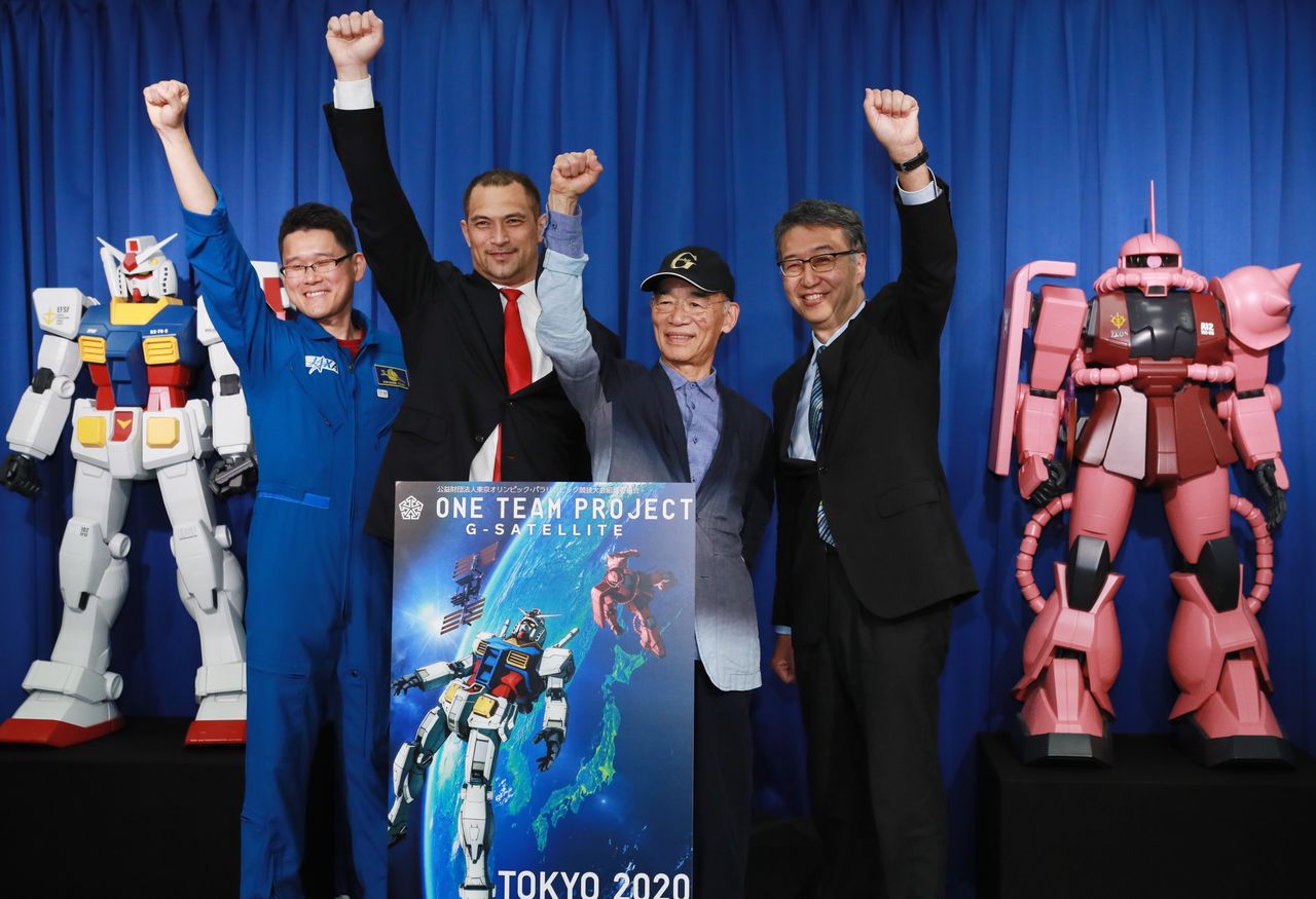 El director de Mobile Suit Gundam, Tomino Yoshiyuki (tercero por la izquierda), levanta el puño triunfante después de la rueda de prensa ofrecida en Chiyoda-ku (Tokio) el 15 de mayo de 2019 con ocasión de la presentación del proyecto “G-Satellite uchū e” (“¡G-Satellite, al espacio¡”). (Fotografía: Jiji Press)