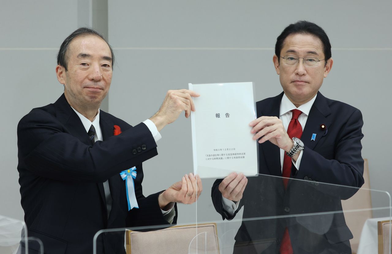El primer ministro Kishida Fumio (derecha) recibe el informe final de manos de Seike Atsushi, presidente del panel que discute las medidas para garantizar la continuidad de la corona imperial, el 22 de diciembre de 2021 en la Oficina del primer ministro. (Jiji Press)