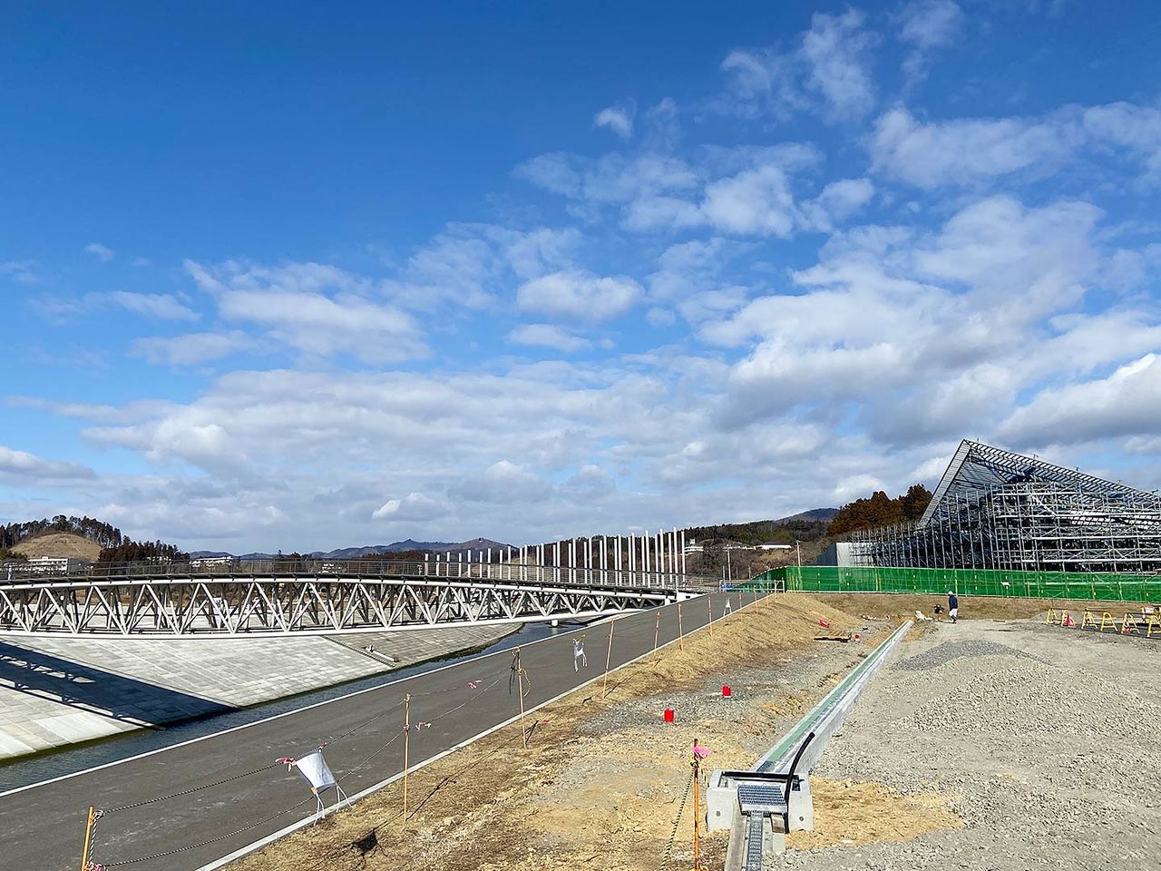 Tras el desastre, la altitud de la ciudad se elevó unos diez metros y se reconstruyó el puente sobre el río Hachiman. Al fondo a la derecha se observan las obras del monumento conmemorativo 311 Minamisanriku, diseñado por el arquitecto Kuma Kengo.